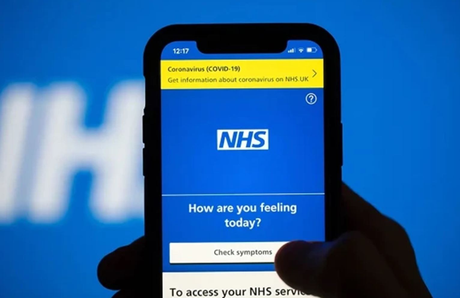 A hand holding a smartphone with the NHS App