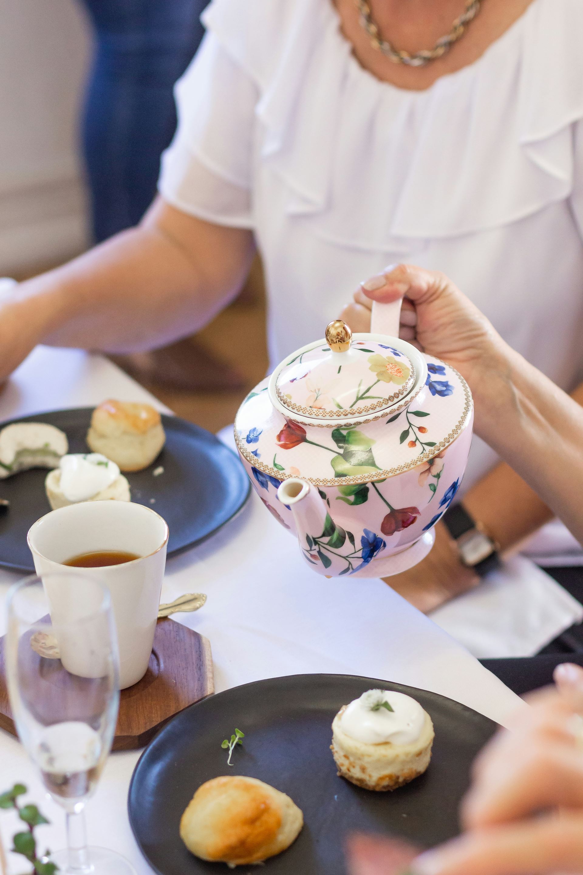 a china pot of tea being poured into a cup