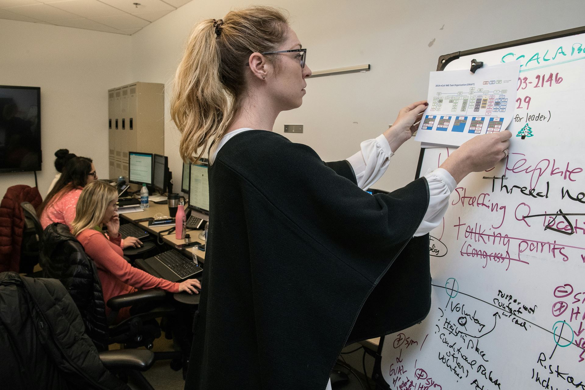a female office working putting up a poster on a board